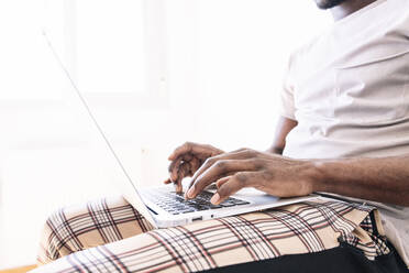 Young businessman typing on laptop while sitting and working at home - JCMF00838