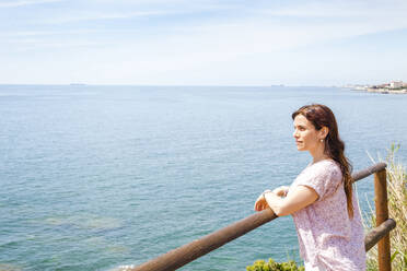 Frau lehnt an der Reling und schaut auf das Ligurische Meer gegen den Himmel an einem sonnigen Tag - FLMF00232
