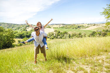 Happy mid-adult couple enjoying countryside on sunny day - FLMF00233