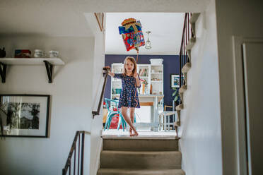Cute young girl standing on stairs with happy birthday balloon - CAVF85090