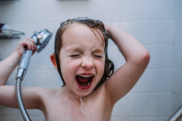 Nahaufnahme eines kleinen Kindes, das beim Haarewaschen unter der Dusche singt - CAVF85094