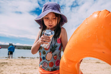 Nahaufnahme eines jungen Mädchens, das am Strand Saft trinkt - CAVF85101