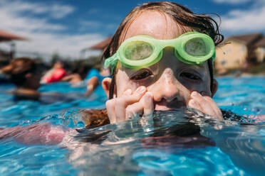 Young child wiping face in pool on summer day - CAVF85103