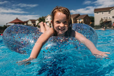 Straight on shot of young girl floating in pool - CAVF85105