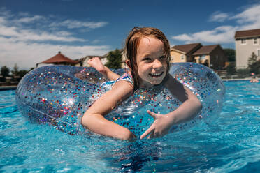 Mittlere Aufnahme eines jungen Mädchens, das im Pool der Nachbarschaft schwimmt - CAVF85108