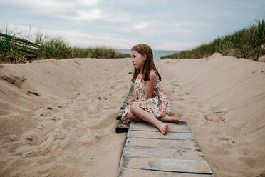 Young girl sitting on pathway going out to lake michigan - CAVF85117