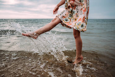 Young girl in dress splashing water in lake Michigan - CAVF85118