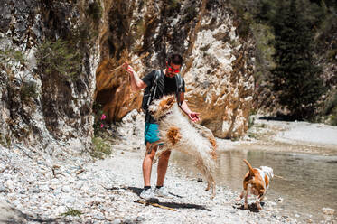 Junger Mann spielt mit Hunden am Fluss Canyon - CAVF85134