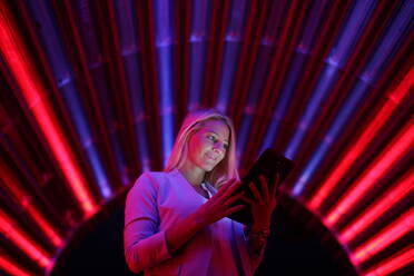 Frau mit digitalem Tablet gegen beleuchtete Lichter - EYF05466