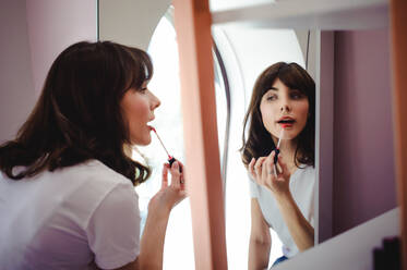 Close-Up der jungen Frau Anwendung roter Lippenstift vor dem Spiegel zu Hause - EYF05467