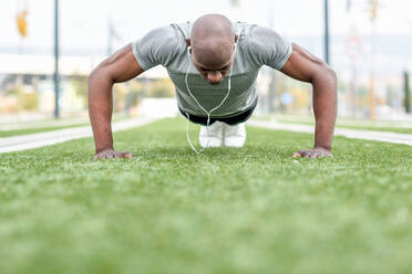 Surface Level View Of Man Doing Push-Ups On Grassy Field - EYF05475