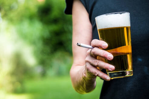 Midsection of Woman Having Beer While Smoking Cigarette Outdoors - EYF05571