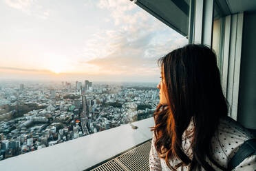 Woman Looking At City Through Window Against Sky - EYF05605