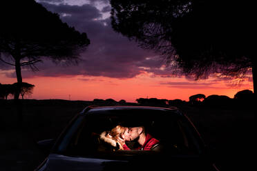 Junges Paar küsst sich im Auto bei Sonnenuntergang - EYF05634