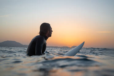 Seitenansicht des Mannes Surfen im Meer gegen den Himmel bei Sonnenuntergang - EYF05680