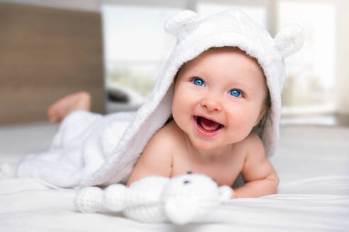 Nahaufnahme von niedlichen Baby lächelnd, während auf dem Bett liegend - EYF05707