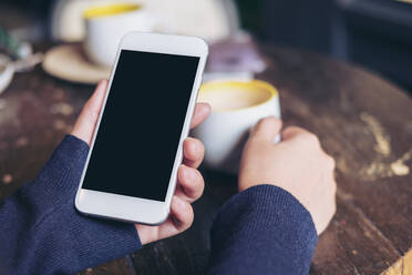 Nahaufnahme einer Frau mit Mobiltelefon und Kaffeetasse - EYF05713