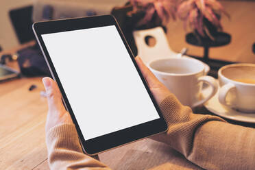 Cropped Hands Of Woman Holding Digital Tablet Over Table In Cafe - EYF05716