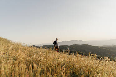 Aktiver älterer Mann, der die Landschaft betrachtet, während er auf einem Berg steht - AFVF06682