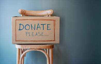 Donation Box On Wooden Chair Against Wall - EYF05780