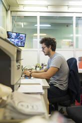 Junger Mann, der einen Computer bei der Arbeit im Büro benutzt - MTBF00435