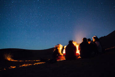 Menschen genießen Lagerfeuer in der Wüste bei Nacht - EYF05802