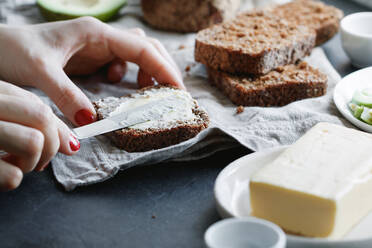 Close-Up Of Woman Applying Butter On Bread In Plate On Table - EYF05841