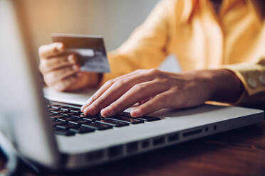 Cropped Hand des Geschäftsmannes hält Kreditkarte während der Verwendung von Laptop im Büro - EYF05924