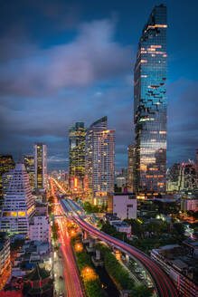 High Angle View Of Light Trails On Road Amidst Modern Buildings Against Cloudy Sky At Night - EYF05932