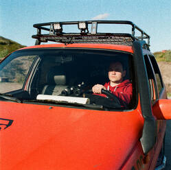 Ein Mann sitzt am Steuer eines Autos mit einer Landkarte und einem Fernglas - CAVF85273