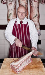 Butcher carving meat in shop - CAVF85293