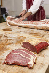 Butcher carving meat in shop - CAVF85294