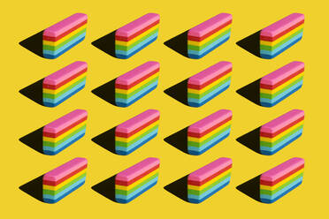 Pattern of rainbow colored erasers against yellow background - XLGF00203