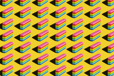 Pattern of rainbow colored erasers against yellow background - XLGF00204