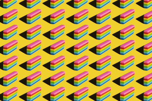 Pattern of rainbow colored erasers against yellow background - XLGF00204