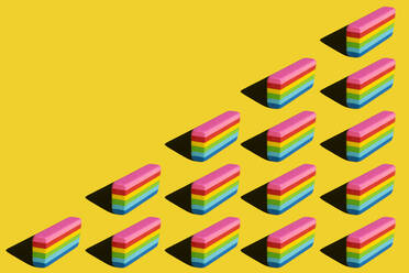 Pattern of rainbow colored erasers against yellow background - XLGF00205