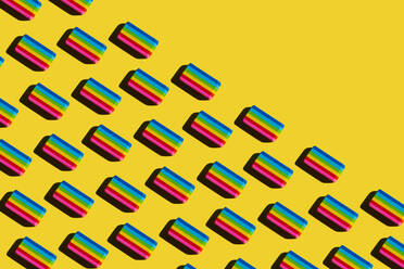 Pattern of rainbow colored erasers against yellow background - XLGF00207