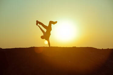 Silhouette Person Doing Handstand Against Sky During Sunset - EYF05948