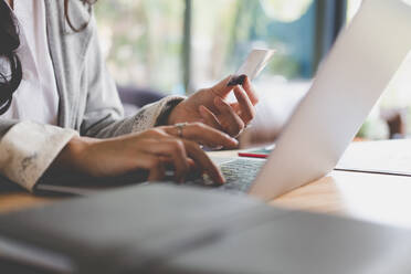 Midsection Of Woman Making Credit Card Payment Over Laptop On Table At Home - EYF06041