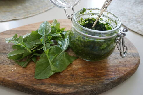 High Angle View of Dandelion Pesto Sauce auf Schneidebrett gegen grauen Hintergrund - EYF06042