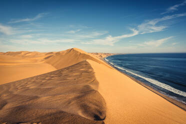 Scenic View Of Sand Dunes By Sea Against Blue Sky - EYF06203