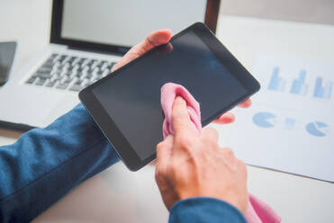 Cropped Hand von Geschäftsmann Reinigung Digital Tablet Bildschirm am Schreibtisch im Büro - EYF06215