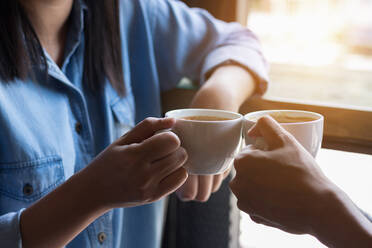 Midsection of Frau Toasting Kaffee mit Freund durch Fenster im Café - EYF06217