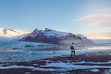 Rear View Of Man Standing By Lake Against Snowcapped Mountains - EYF06221