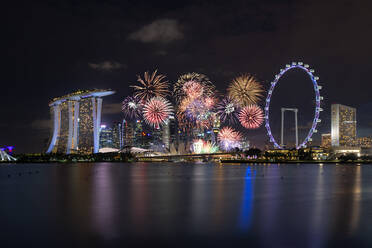 Firework Display Over Illuminated City Against Sky At Night - EYF06227