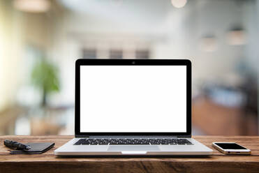 Close-Up Of Laptop With Mobile Phone On Table In Office - EYF06247