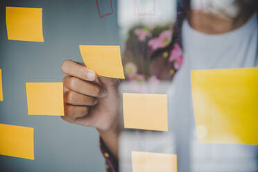 Midsection Of Businesswoman Holding Adhesive Note On Glass - EYF06256