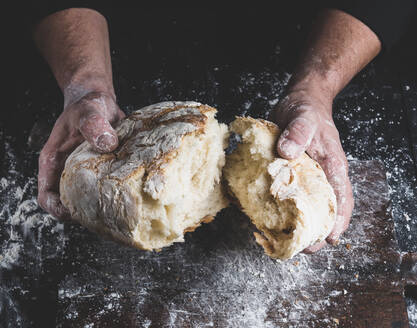 Nahaufnahme einer Person, die Brot am Tresen bricht - EYF06263