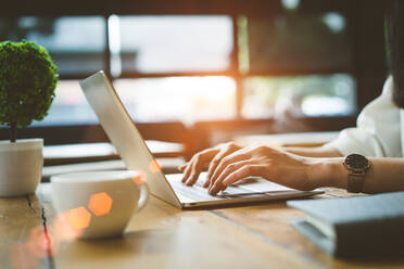 Cropped Image Of Woman Using Laptop At Desk In Restaurant - EYF06265