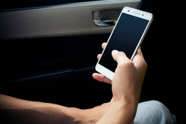 Abgeschnittenes Bild eines Mannes, der ein Mobiltelefon benutzt, während er im Auto sitzt - EYF06272